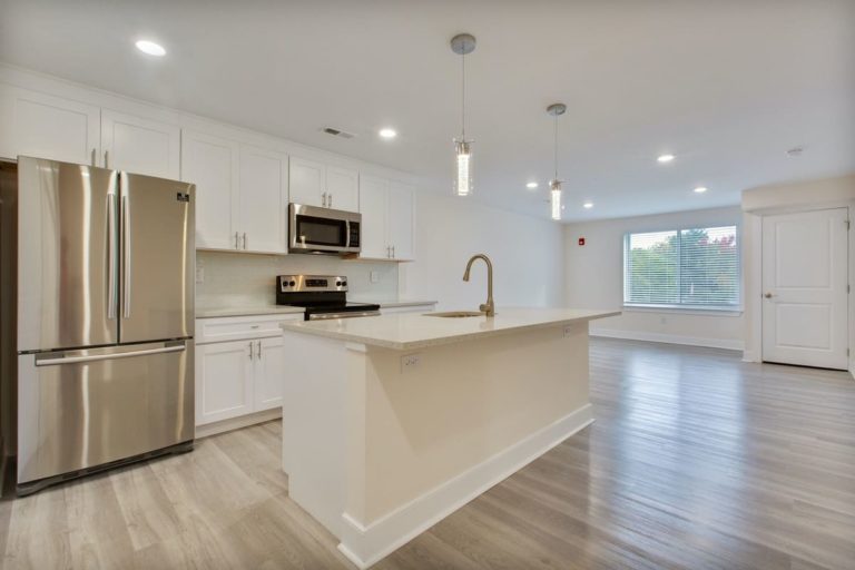 Open-plan apartment kitchen at The View at Manayunk with an island, white cabinets and stainless steel appliances