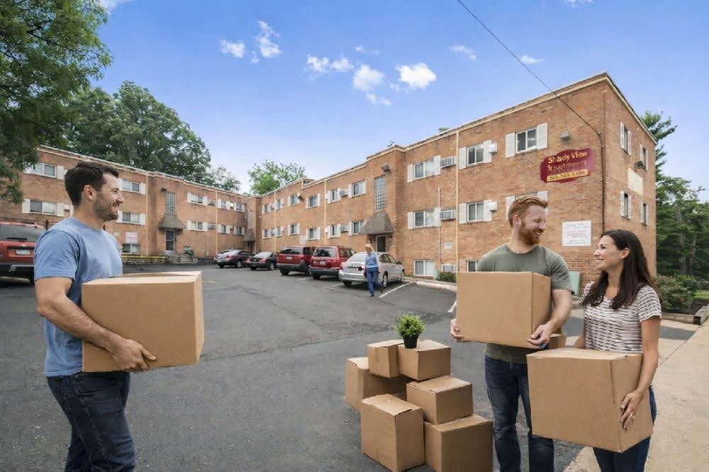 Tenants carrying moving boxes outside the apartment building on move-in day.